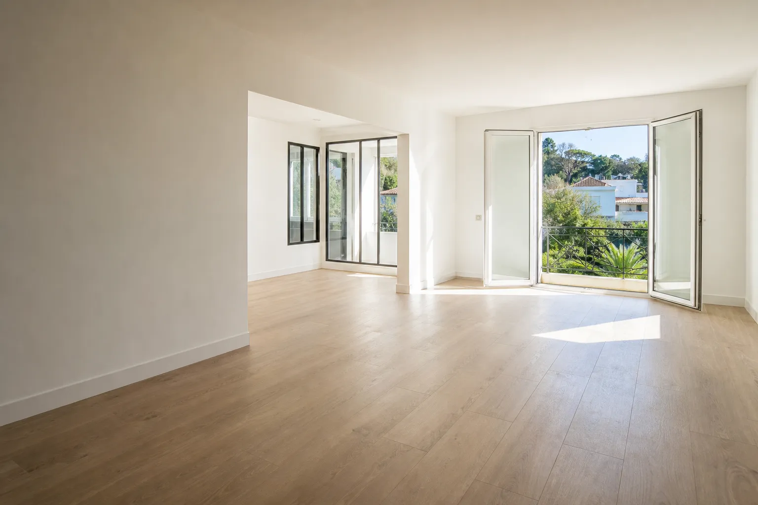 Séjour d’appartement méditerranéen lumineux, parquet clair, grande fenêtre ouverte
